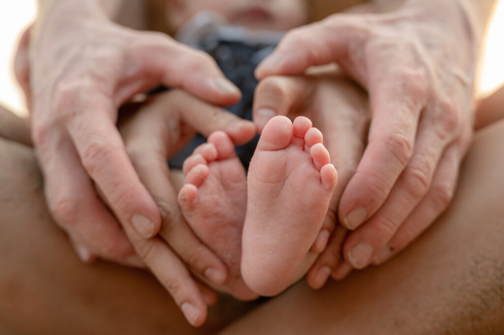Close-up of baby's feet. Mother holding baby.Happy family at sunset.Holiday Family